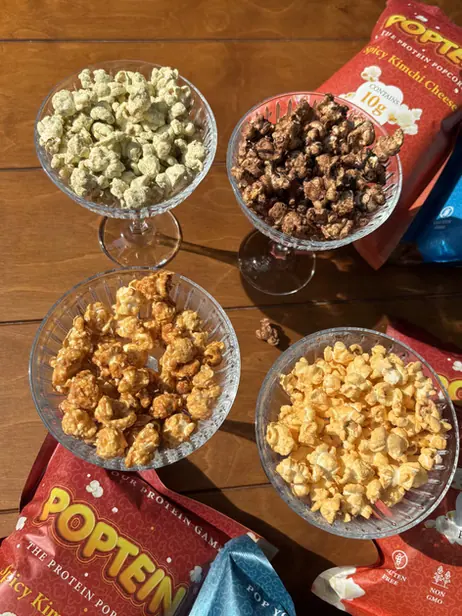 Four glass bowls of Poptein popcorn — herb, brownie, caramel and peanut butter