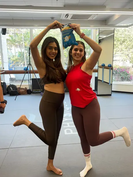 Two dancers holding a Poptein pack overhead in a studio